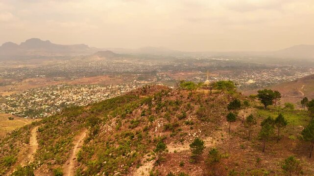 A broad view of Blantyre spreads beyond a hazy Michiru Mountain ridge, with a distant hilltop cross and surrounding mountains.