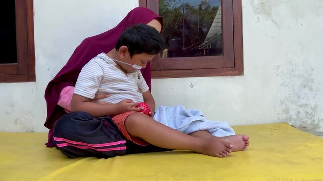 Mother supporting a child with a disability and medical nasal cannula in a home setting