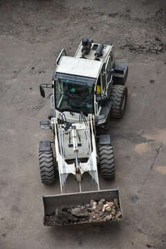 Aerial view of construction site where a front loader is loading soil, rocks, and debris into a dump truck, industrial work, excavation, and earthmoving processes