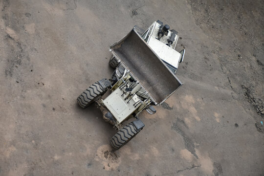 Aerial view of construction site where a front loader is loading soil, rocks, and debris into a dump truck, industrial work, excavation, and earthmoving processes