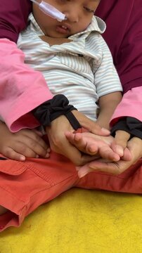 Mother providing physiotherapy to a child with a disability and nasogastric feeding tube at home