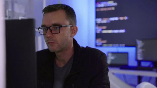 Software developer writing code on computer monitor in office