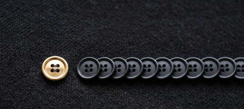 Single Gold Button Standing Out From Row of Black Buttons