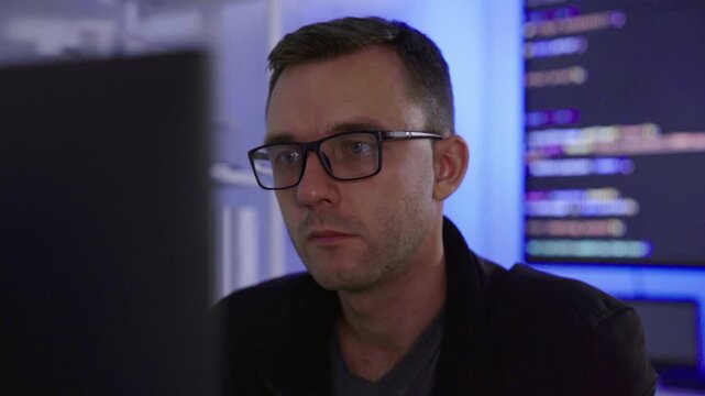 Software developer writing code on computer monitor in office