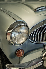Detailed view of the front corner of a light green classic car. © SKfoto GE