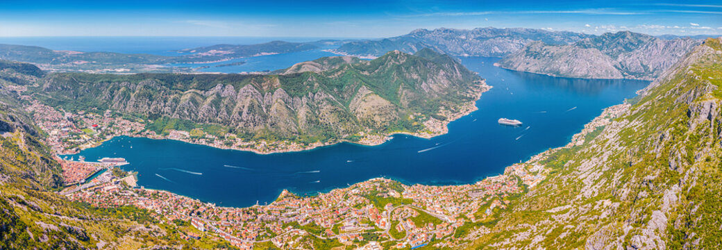 Panoramic view showing the Bay of Kotor, Montenegro, with historical towns nestled between dramatic mountains and the Adriatic Sea