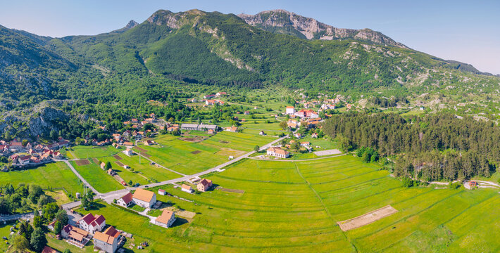 Njegusi village showcasing traditional houses, roads, and vibrant green agricultural fields from an aerial perspective in rural Montenegro