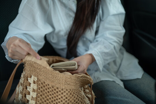 Close up of a woman storing personal belonging in woven bag while traveling in back seat of taxi car