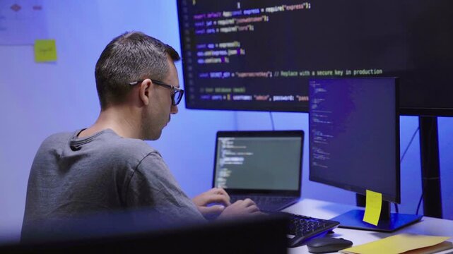 Software developer writing code on computer monitor in office