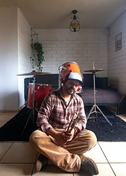 A drummer sitting on the floor next to a drum set