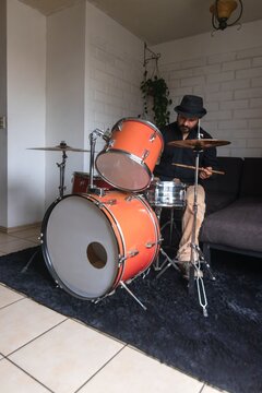 Front view of a man practicing drums in his living room