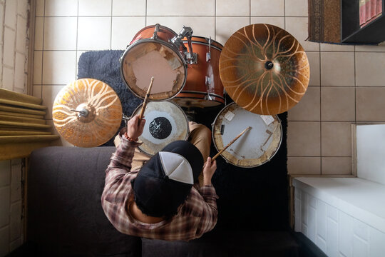 Flat lay perspective of a drummer practicing drum set indoors, top-down shot