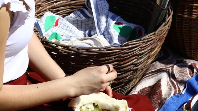 Young girl, woman is having breakfast, taking food to eat at open in retro style, like old times. Health care and food concept in traditional rural meal, homemade dry meat, pickle, bread, harvest time