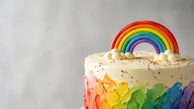 Rainbow cake with colorful icing and cheerful rainbow topper creates festive atmosphere for celebrations and joyful gatherings