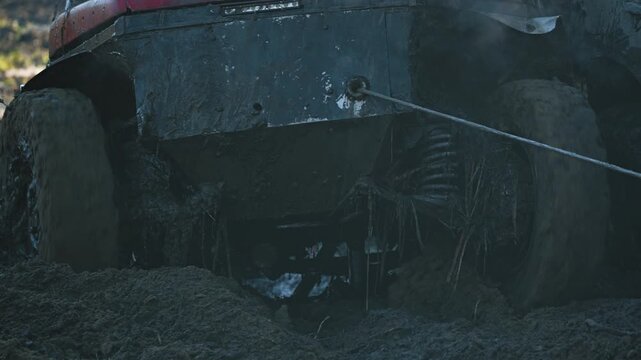 A close-up of a powerful 4x4 driving through deep sand. A winch cable pulls SUV out of the difficult terrain during an extreme auto race. Steam rises from the hot engine. It's a tense, powerful scene
