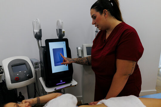 Technician operating aesthetic machine for body contouring treatment
