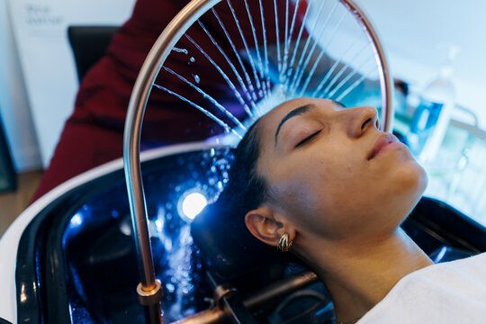 Woman enjoying a relaxing hair washing treatment at salon