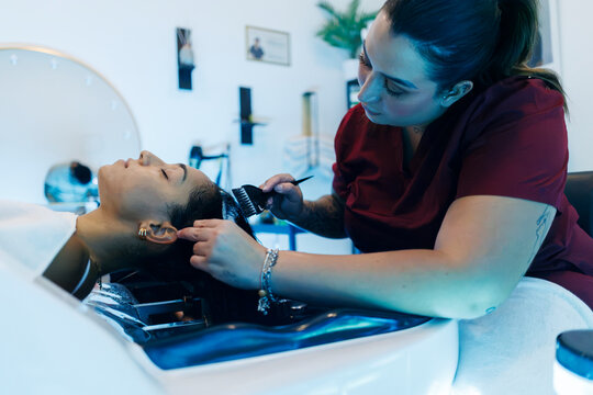 Hairdresser applying treatment to client's hair in salon