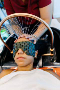 Woman receiving relaxing scalp treatment with jade eye mask