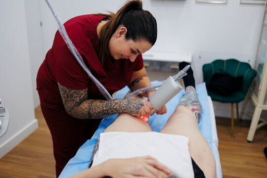 Technician performing laser hair removal treatment on client leg