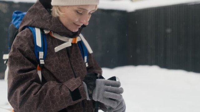 Caucasian woman hiking in winter snow, stopping and adjusting backpack strap then smiling. Clip is perfect for outdoor recreation commercials, winter gear ads, and travel promotions