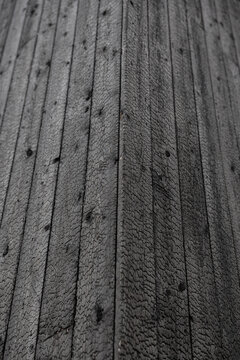 Detailed close-up of black charred timber boards with cracked grain, knots, vertical lines, and a pronounced corner formed by Shou Sugi Ban cladding