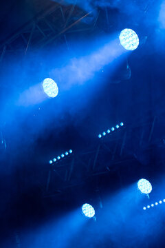 Bright blue LED stage spotlights project powerful beams through theatrical fog on a concert lighting rig, creating a dramatic live event atmosphere with copy space