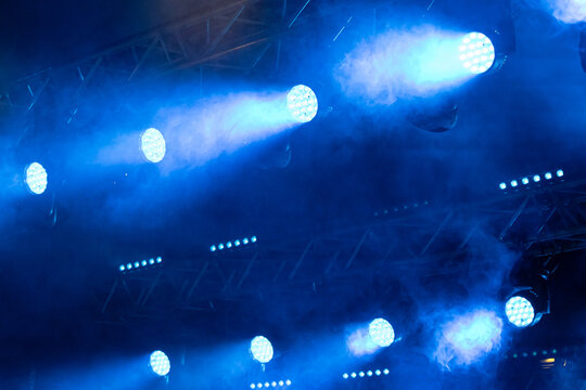 Bright blue LED stage spotlights project powerful beams through theatrical fog on a concert lighting rig, creating a dramatic live event atmosphere with copy space