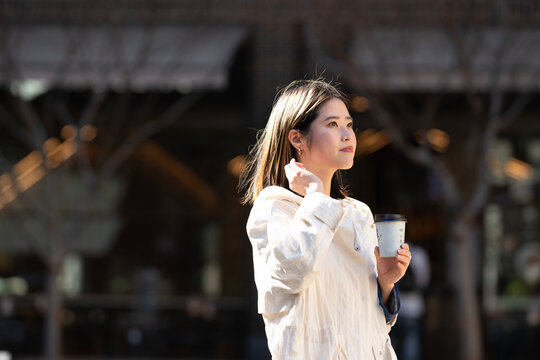 街の中でコーヒーを片手に歩いている女性