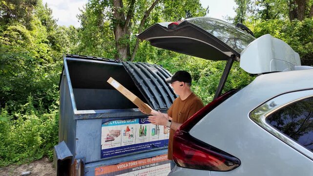 Man dropping off cardboard at a recycling center dumpster