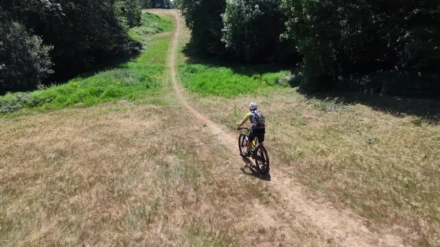 Very fast decent on Mountain bike grassy hill drone follow tracking shot