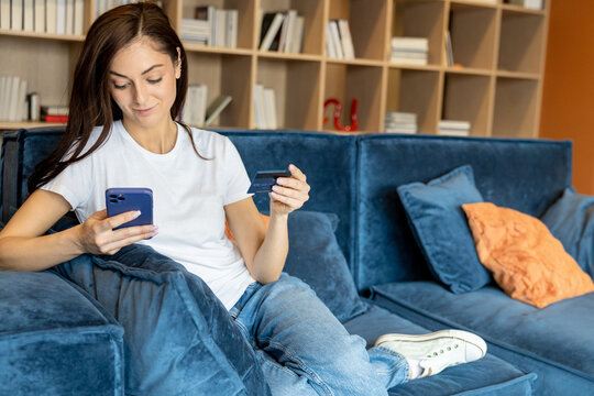 Long-haired woman with a phone and a credit card in hands