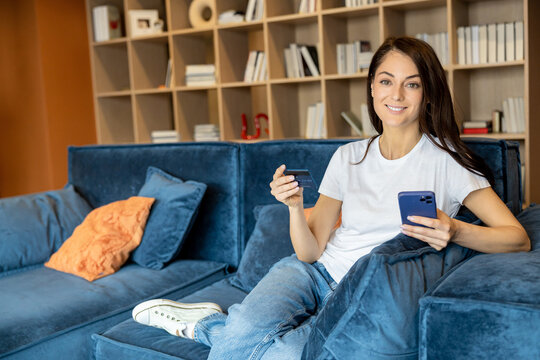 Long-haired woman with a phone and a credit card in hands