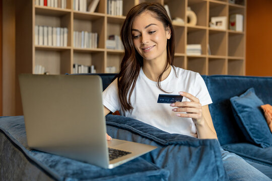 Young woman buying something online and looking contented