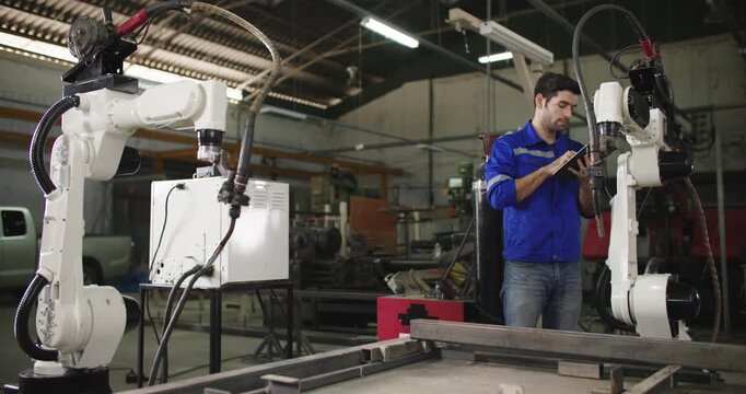 Professional industrial engineer caucasian man using digital tablet for checking, maintenance and repair automation robot arms machine for production in manufacturing industry. Innovation Technology.
