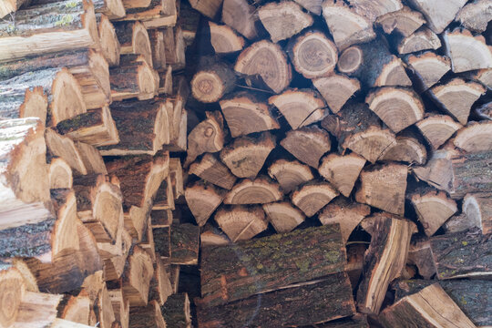 Pile of split firewood stacked for drying and winter heating. Natural wood texture, renewable fuel and rural household concept.