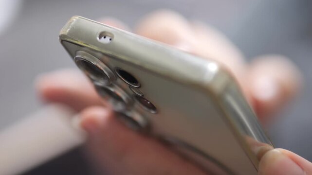 Close-up of smartphone camera module and lenses. Fingers hold the device securely. No visible facial expression. Highlights phone design features. Ideal for tech advertising