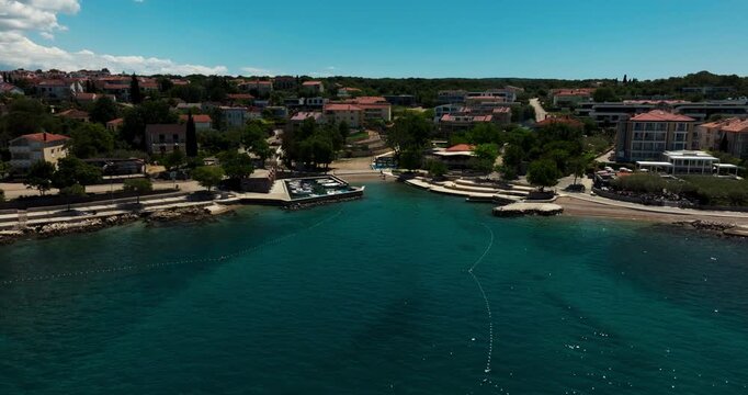Malinska on Krk Island, Croatia, with turquoise Adriatic water, waterfront homes, small harbor and green coastal surroundings.