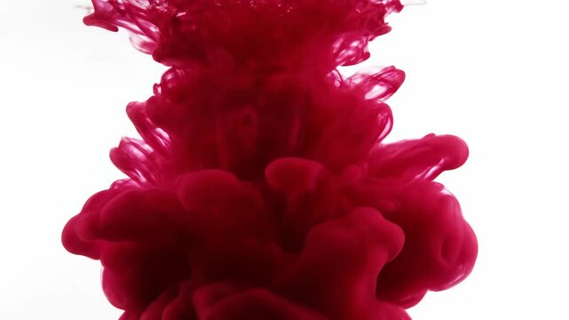 Dramatic deep red crimson ink dropping into water, swirling and spreading on a white background, creating an abstract liquid cloud motion.