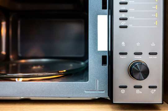Empty microwave oven with open door. Closeup on buttons and knob on control panel for adjust mode and timer of microwave.