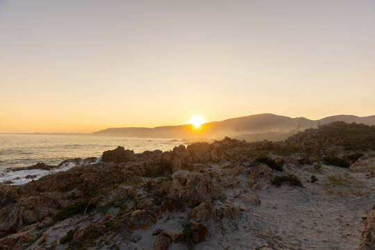 beautiful rugged rocky coastline of Kammabaai Beach, Hermanus, South Africa at sunset and dusk