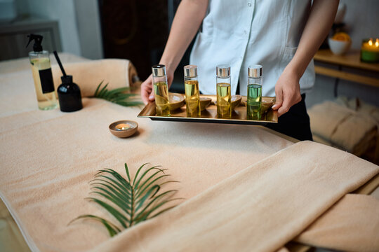 Close up of massage therapist organizing aromatic oils for luxury spa treatment.