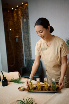 Professional female spa therapist preparing massage oils before treatment.