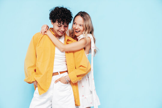 Happy beautiful romantic teenage couple. Smiling handsome caucasian man and young woman in summer clothes posing in studio, hugging sharing emotions, cheerful and happy. Isolated on blue