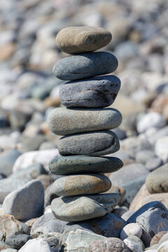 Carefully balanced stack of stones on pebble beach under bright sunlight