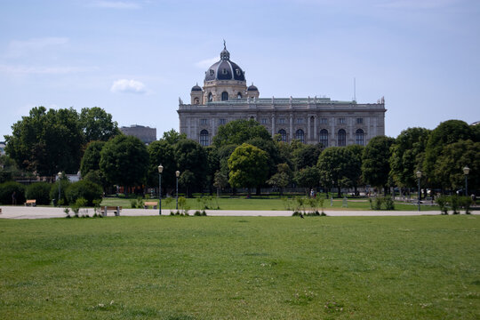 Facciata monumentale del Museo di Storia Naturale di Vienna sormontato dalla sua cupola, visto dall'ampio prato verde e dagli alberi del parco pubblico Volksgarten, Austria.