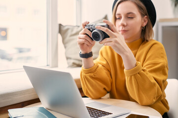 Naklejka premium Female photographer with camera, laptop and smart phone at cafe