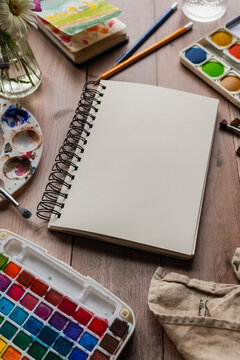 Watercolor painting setup with a blank sketchbook