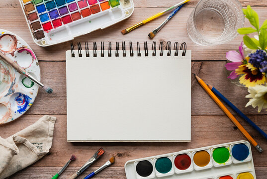 Blank sketchbook on desk with watercolor art supplies