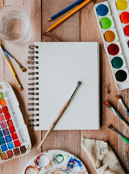 Blank sketchbook with watercolor paint supplies flat lay